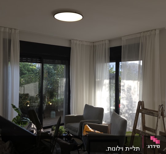 סולם וחלונות עם וילונות בחדר מואר